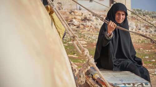 Eine Frau neben einer provisorischen Unterkunft.