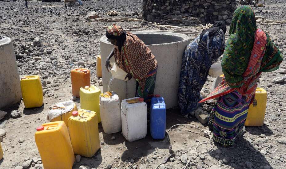 Menschen holen mit Kanistern Wasser vom Brunnen