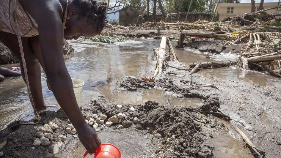 Wetterextreme treffen oft die Ärmsten - Eine Frau schöpft Wasser nach Hurrikan Mathew in Haiti.