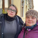 Zwei Frauen aus der Ukraine in warmer Kleidung stehen nebeneinander auf einem Gehweg, Polen 2022.
