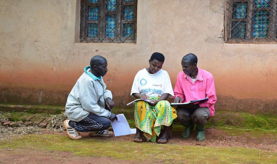 Eine Frau und zwei Männder beugen sich über zwei Hefte.
