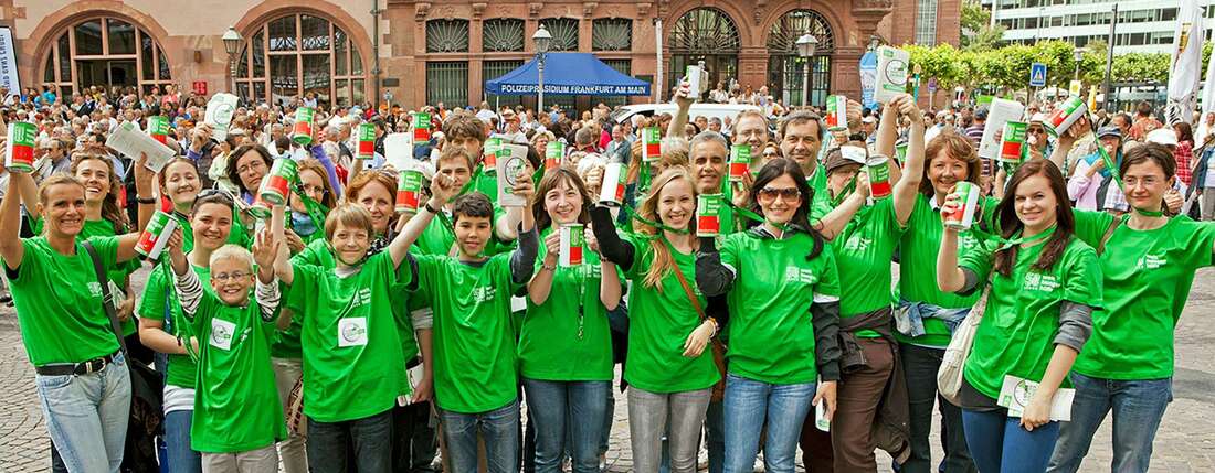 Menschen mit grünen T-Shirts schauen lachend in die Kamera.