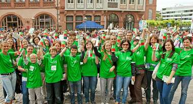 Menschen mit grünen T-Shirts schauen lachend in die Kamera.