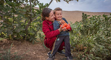Evin, 23, erntet mit ihrem kleinen Sohn selbst angebaute Tomaten im Irak