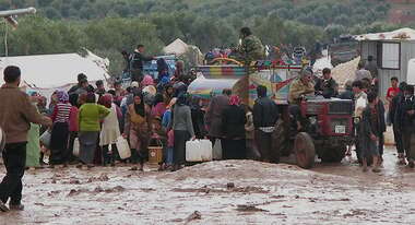 Viele Flüchtlinge stehen vor einem LKW, der sie mit Wasserkanistern versorgt.rhalten.