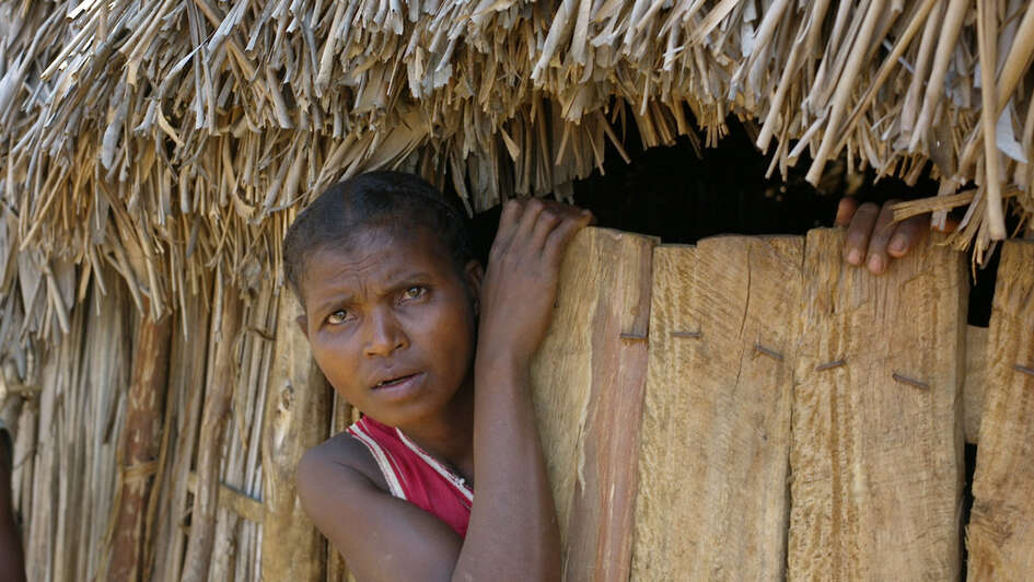 Eine Frau schaut aus ihrer Hütte in Madagaskar.