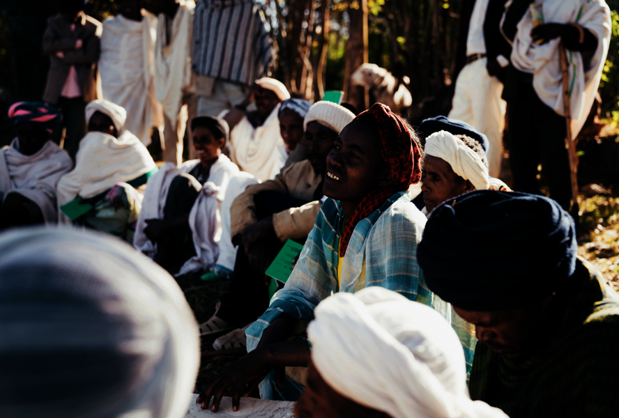 Frauen und Männer sitzen während eines Workshops auf dem Boden und hören zu.