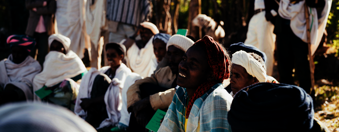 Frauen und Männer sitzen während eines Workshops auf dem Boden und hören zu.