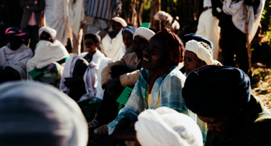Frauen und Männer sitzen während eines Workshops auf dem Boden und hören zu.