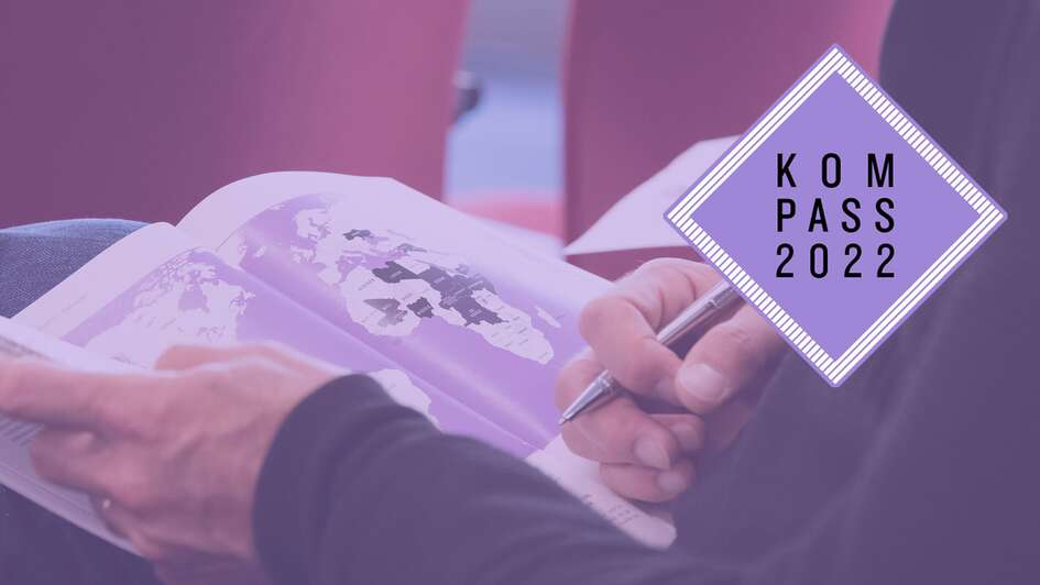Bei der Pressekonferenz zum Kompass 2022 in Berlin – eine Person hält die Druckausgabe des Kompass 2022 in den Händen, aufgeschlagen ist eine Weltkarte.