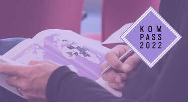 Bei der Pressekonferenz zum Kompass 2022 in Berlin – eine Person hält die Druckausgabe des Kompass 2022 in den Händen, aufgeschlagen ist eine Weltkarte.