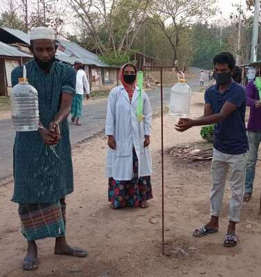 Verschiedene Menschen waschen sich an Hygienestationen die Hände.