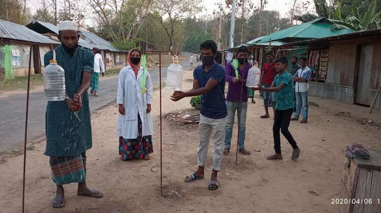 Verschiedene Menschen waschen sich an Hygienestationen die Hände.