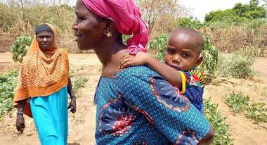 Eine Frau mit ihrem Baby auf dem Rücken.