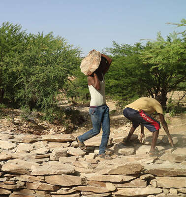 Männer tragen Steine und bauen einen Damm