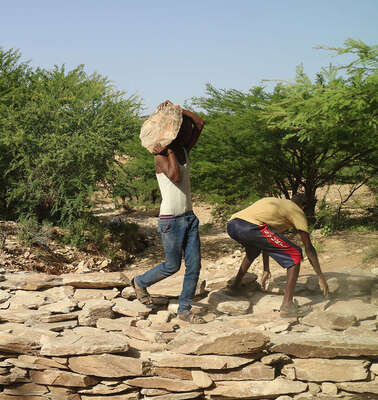 Männer tragen Steine und bauen einen Damm