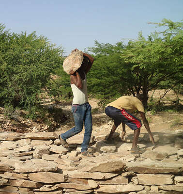 Männer tragen Steine und bauen einen Damm