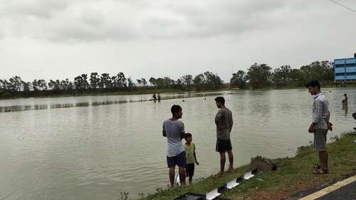 Menschen stehen vor überfluteten Feldern nach Zyklon Amphan, Indien.