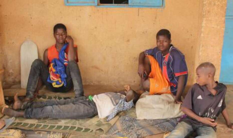 Jugendliche sitzen vor einem Haus, Burkina Faso.