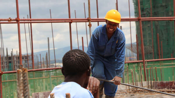 Zwei Männer im SkillUp!-Projekt sprechen auf einer Baustelle in Kenia miteinander.