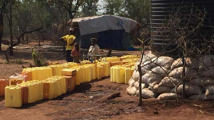 Flüchtlinge zapfen sich Wasser aus den Tanks in Kanister.