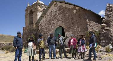Dorfbewohner stehen vor einer Kirche.