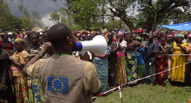 Ein Mann spricht durch ein Megaphon zu einer Menschenmenge in Katoto, Kongo