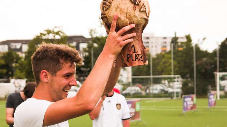 2018-zerohunger-footballcup-pokal-fabian-jauss-welthungerhilfe.jpg Glückliches Strahlen: Einer der Spieler aus dem Gewinnerteam hält den Pokal vom ersten #ZeroHunger-FootballCup 2018 in die Höhe.