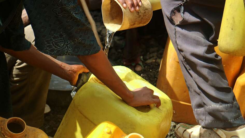 Menschen befüllen gelbe Kanister mit Wasser