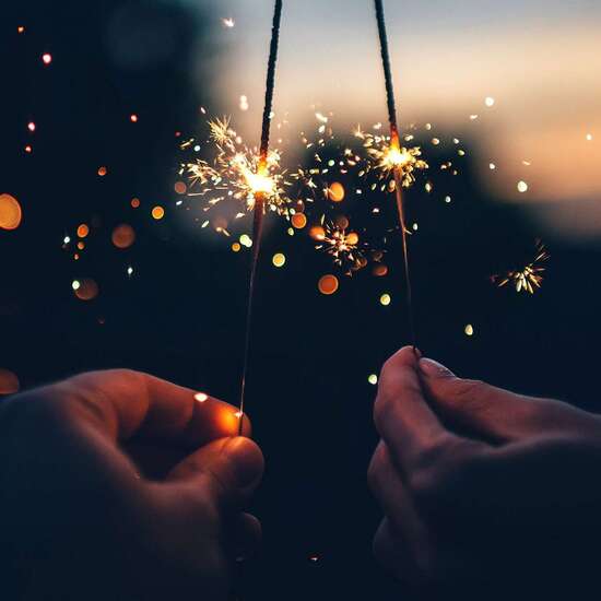 Anlassspende zu Silvester: Nahaufnahme von zwei Händen mit Wunderkerzen