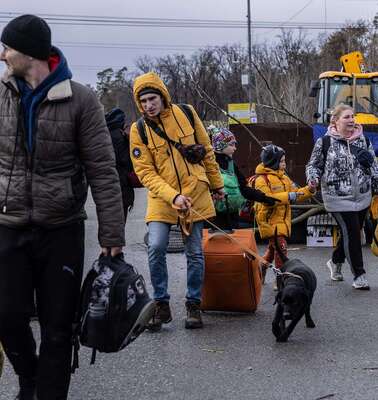 Jetzt für die Ukraine spenden. Mehrere Menschen mit Koffern und Taschen gehen auf die Kamera zu.
