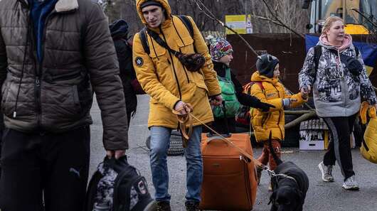 Jetzt für die Ukraine spenden. Mehrere Menschen mit Koffern und Taschen gehen auf die Kamera zu.