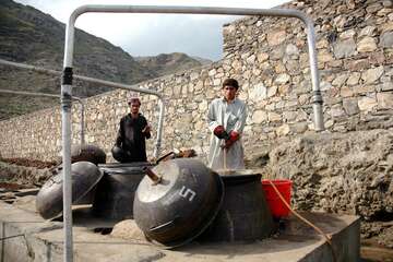 Zwei Männer an einer Dampf-Destillationsanlage