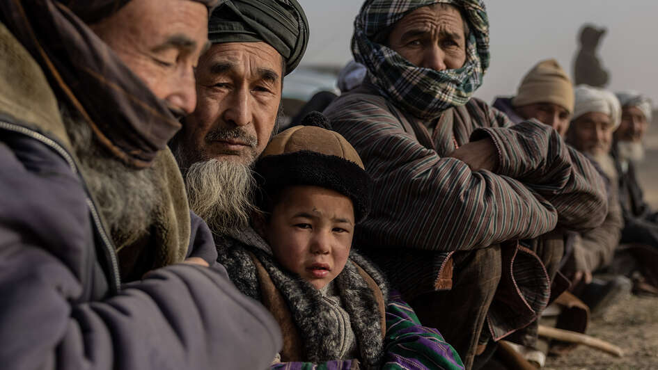Mehrere Männer sitzen nebeneinander, dazwischen ein kleines Kind.