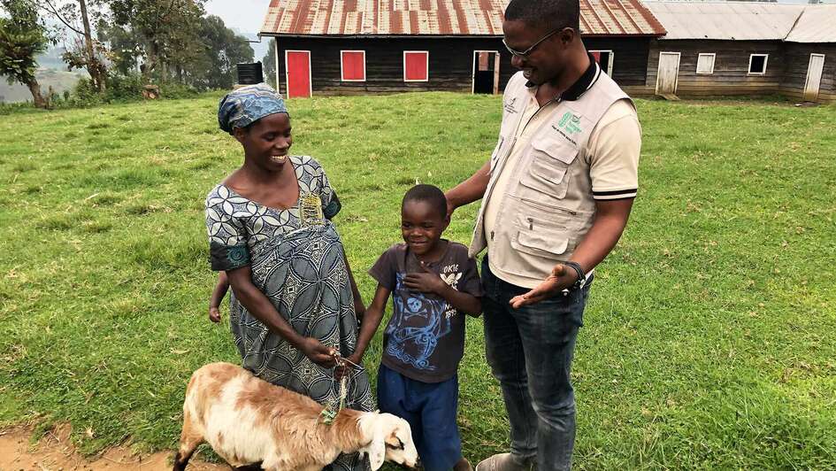 Eine schwangere Frau, ein kleiner Junge und ein Mann, vor ihnen ein Schaf.