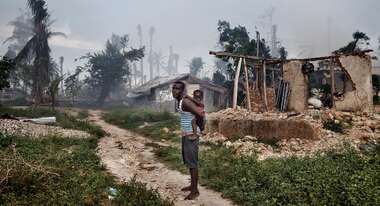 Ein Mann mit seiner Tochter vor den Ruinen eines Hauses in Grand Anse.