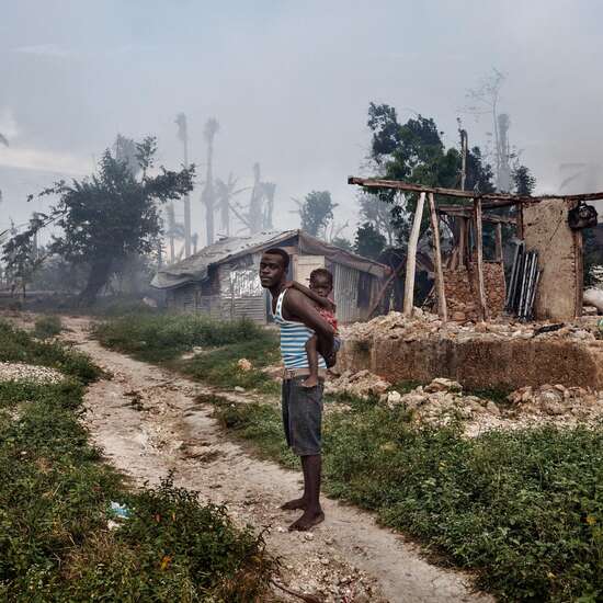 Ein Mann mit seiner Tochter vor den Ruinen eines Hauses in Grand Anse.