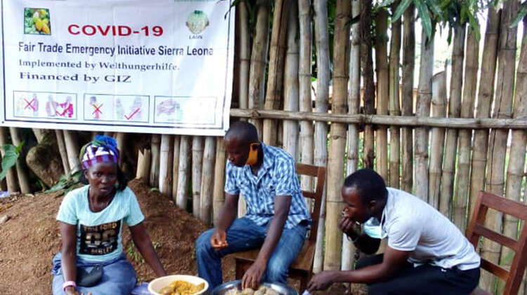 Eine Frau und zwei Männer sitzen an einem kleinen Tisch und essen.