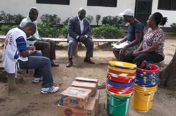 Fünf Leute sitzen in einem Kreis zusammen, einer erklärt