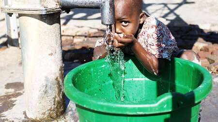 Junge trinkt frisches Wasser aus dem Hahn