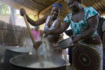 Köchinnen bereiten in zwei großen Töpfen das Schulessen zu. 