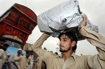 Ein Flüchtling transportiert seinen Besitz auf dem Kopf.
