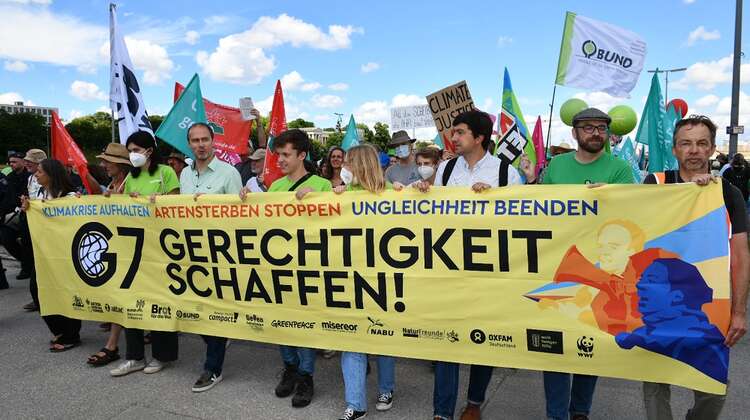Demonstrierende tragen ein Banner mit der Aufschrift "Gerechtigkeit schaffen"