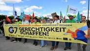 Demonstrierende tragen ein Banner mit der Aufschrift "Gerechtigkeit schaffen"