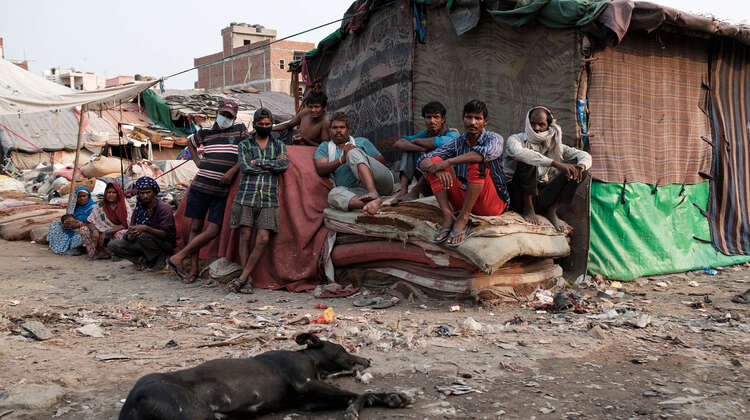 Mehrere Männer sitzen auf einem Stapel Matratzen.