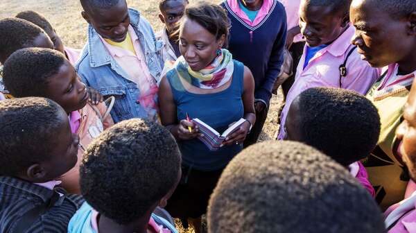Frau steht in der Mitte einer Gruppe von Schülern