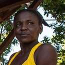 Eine Frau und ein Mann auf einer Veranda, die Frau steht am Geländer, der Mann sitzt an der Hauswand.