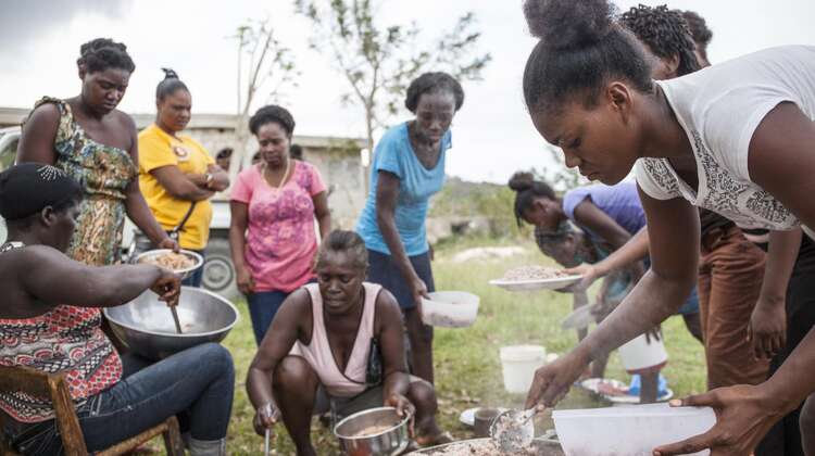 Frauen schöpfen Reis und Fisch auf die Teller.