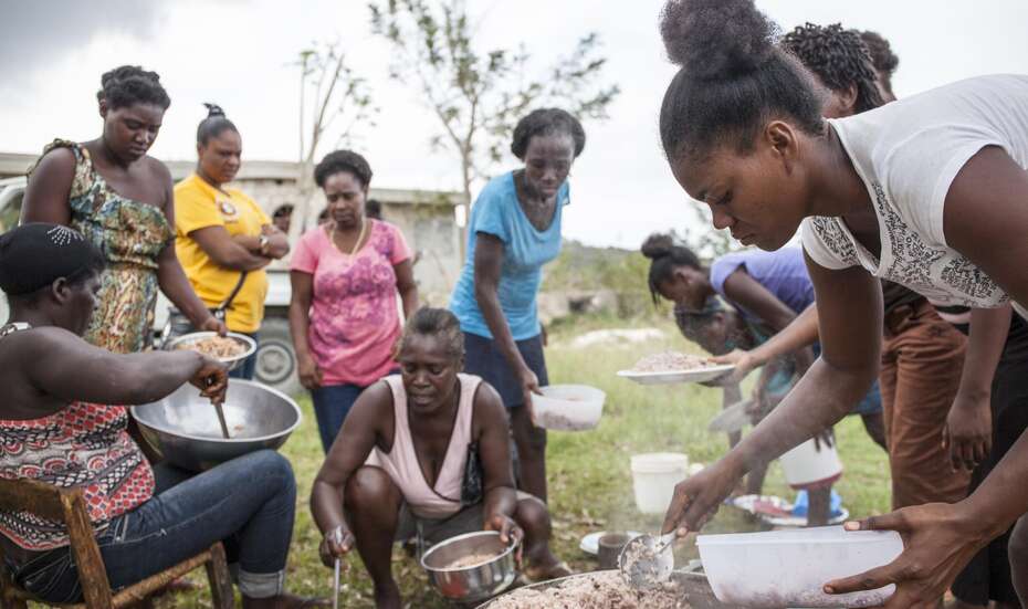 Eine Frau verteilt Lebensmittel an andere Menschen