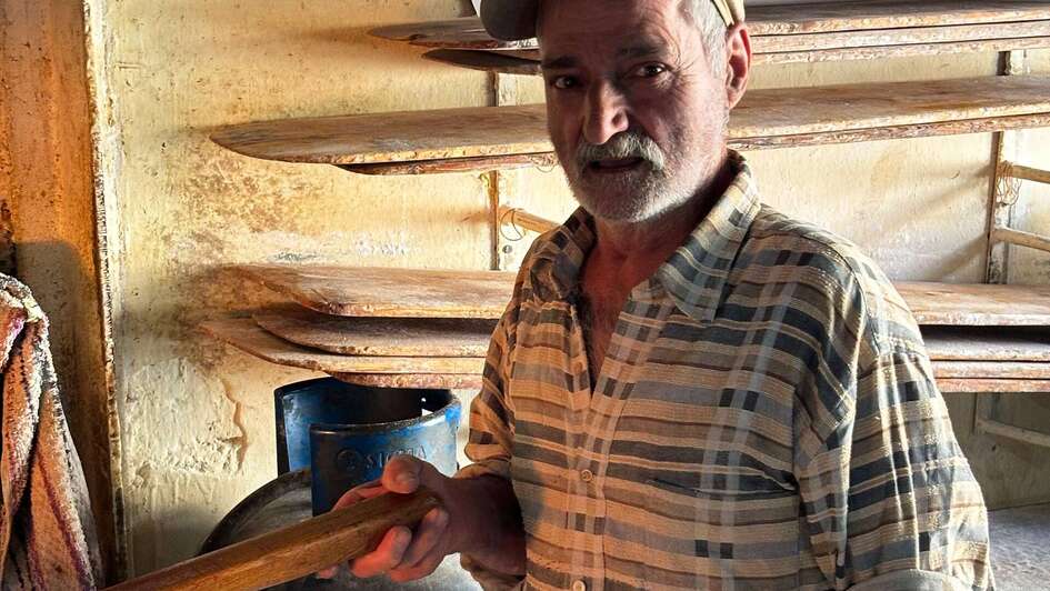 Ein älterer Mann steht in einem Raum, im Hintergrund sieht man leere Regale.